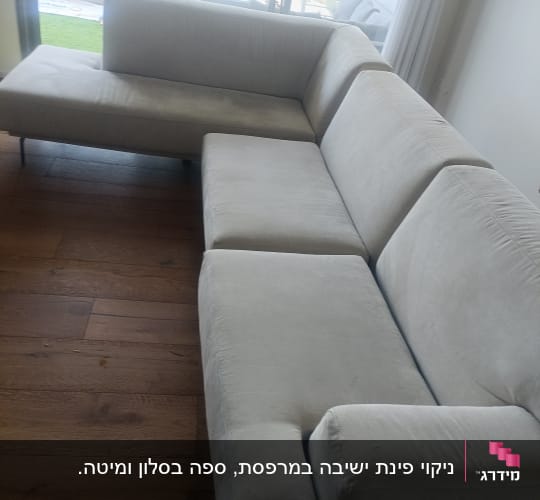 ספה בהירה ליד חלון גדול עם נוף עירוני
